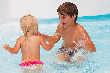 Image showing Little baby girl with her brother swimming in the pool 