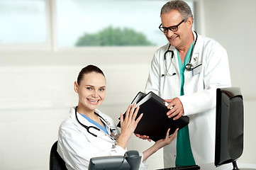 Image showing Male doctor handing over files to female doctor