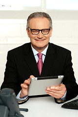 Image showing Senior executive sitting with tablet pc in hands