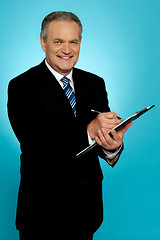Image showing Smiling businessman writing on clipboard