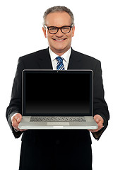 Image showing Senior executive standing with open laptop