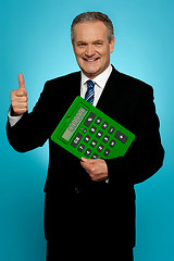 Image showing Businessman showing thumbs up, holding calculator