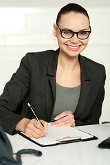 Image showing Secretary writing key business notes on clipboard