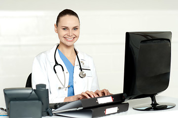 Image showing Smiling female doctor working on computer