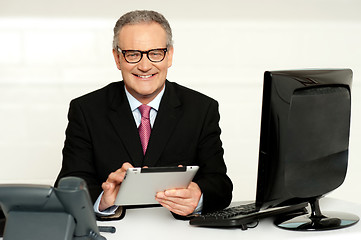 Image showing Aged businessman in glasses using tablet