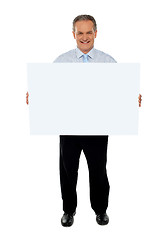 Image showing Confident businessman holding blank billboard
