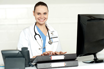 Image showing Cheerful female doctor tying on keyboard