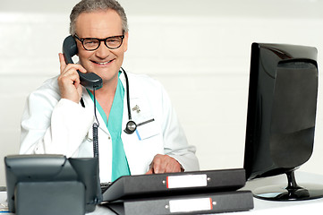 Image showing Aged doctor attending call in front of lcd screen