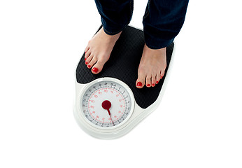 Image showing Woman standing on weighing scale, closeup of legs