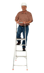 Image showing Worker wearing hard hat climbing ladder