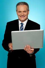 Image showing Smiling aged executive holding laptop