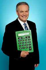 Image showing Senior executive posing with big green calculator