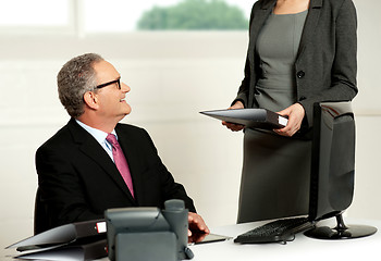 Image showing Smiling aged male boss looking at secretary