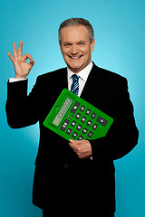 Image showing Confident executive holding calculator and gesturing okay sign