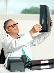 Image showing Aged surgeon holding patients x-ray report