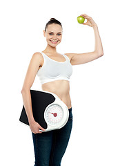 Image showing Fit woman holding weighing machine and green apple