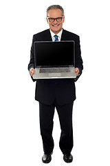 Image showing Aged businessman showing newly launched laptop