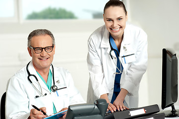 Image showing Doctors team. Female assistant typing on keyboard