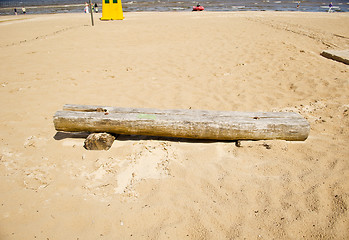 Image showing Old broken wooden bench in sea sand. People relax 