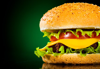 Image showing Tasty and appetizing hamburger on a darkly green