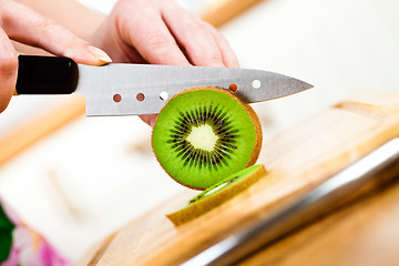 Image showing Woman's hands cutting kiwi