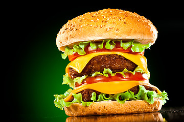 Image showing Tasty and appetizing hamburger on a darkly green