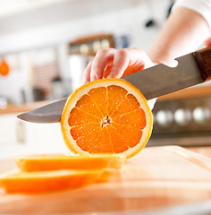 Image showing Woman's hands cutting orange