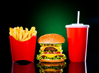 Image showing Tasty hamburger and french fries on a dark green