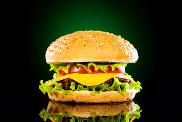 Image showing Tasty hamburger and french fries on a dark