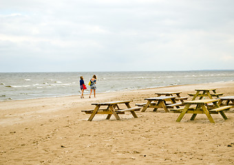 Image showing Wooden benches table sea coast  teenage girls walk 