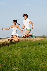 Image showing young happy couple jumping outside in summer 