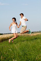 Image showing young happy couple jumping outside in summer 