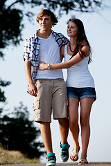 Image showing young woman and man is walking on a road in summer outdoor