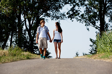 Image showing young woman and man is walking on a road in summer outdoor