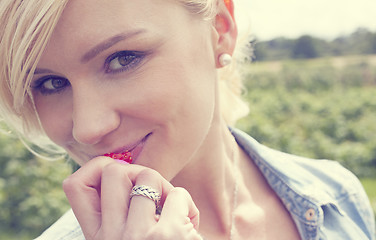 Image showing Attractive blonde enjoying a ripe strawberry