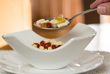 Image showing Spoon of vitamins over bowl of tablets