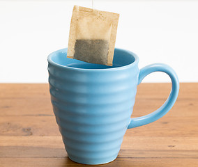 Image showing Brown organic green tea bag lowered in mug