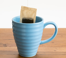 Image showing Brown organic green tea bag lowered in mug