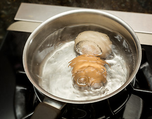 Image showing Two boiling eggs in stainless saucepan