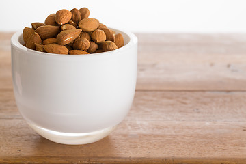 Image showing Bowl of raw almond nuts on wooden table