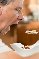 Image showing Senior man eating a spoon of vitamins