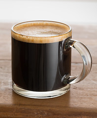 Image showing Black coffee and froth in glass mug wood table