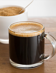Image showing Black coffee and froth in glass mug with sugar