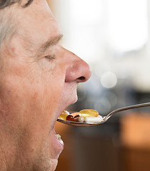 Image showing Senior man eating a spoon of vitamins