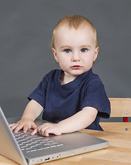 Image showing baby with laptop computer in grey background