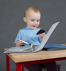 Image showing baby with paperwork and calculator at wooden desk