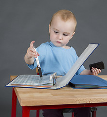 Image showing baby with paperwork at wooden desk