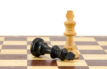 Image showing Black chess king lie near winner white legs 