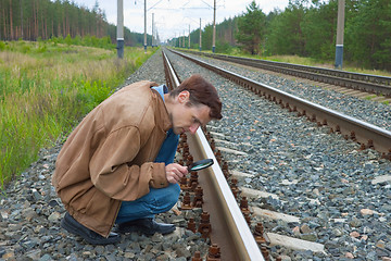 Image showing Man sits on railway with magnifier in hand