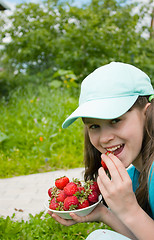 Image showing Little girl eats ripe strawberry